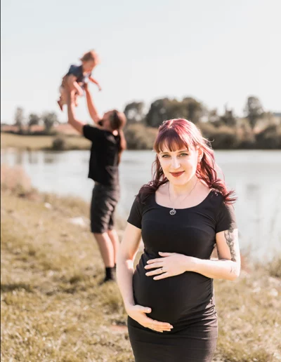 Glückliche Familie beim Babybauch-Fotoshooting im Freien